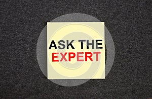 Yellow sticker on the dark gray texture background with text Ask The Expert