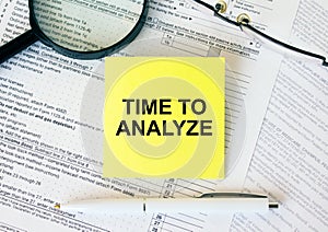 Yellow sticker with text Time To Analyze on financial docs