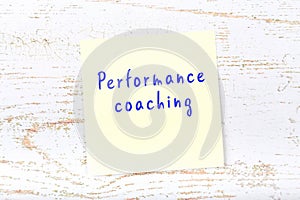 Yellow sticky note with handwritten text performance coaching