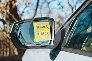Sticky note with 'Mirror, Mirror' on car side mirror
