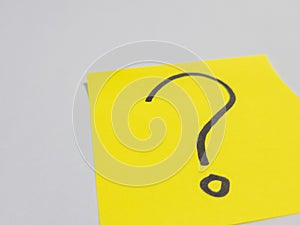 Yellow sticky note with a question mark on a white surface