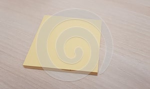 Yellow sticky note without text to be filled on a light wood background