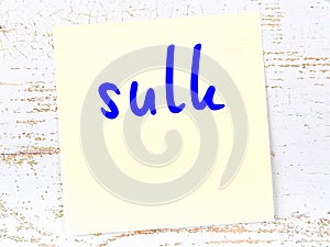 Yellow sticky note on wooden wall with handwritten word sulk photo