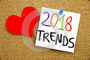 A yellow sticky note writing, caption, inscription Phrase 2018 TRENDS in black ext on a sticky note pinned to a cork