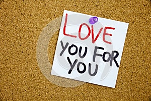 A yellow sticky note writing, caption, inscription Phrase LOVE YOU FOR YOU in black ext on a WHITE sticky note pinned to a cork no