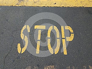 Yellow stop sign on black asphalt with speed bump