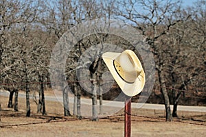 Yellow Straw Cowboy Hat Hanging of Rusty Fence Post