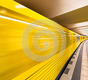 Yellow subway train speeding up on a city station. Business and