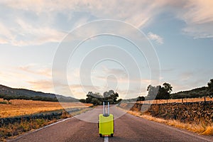 Yellow suitcase on a road in the field