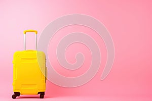 a yellow suitcase is sitting on a pink background