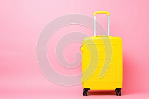 a yellow suitcase is sitting on a pink background