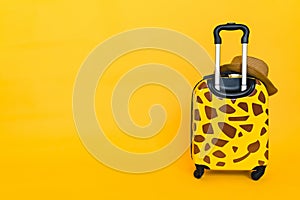 Yellow suitcase on a yellow background. Travel concept banner. Holiday Adventure Trip. Travel bag. giraffe spots, space