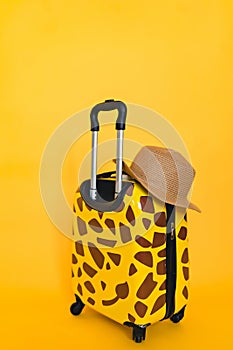 Yellow suitcase on a yellow background. Travel concept banner. vertical photo. giraffe spots, space for text