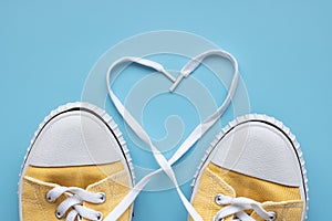 Yellow summer youth sneakers on a blue background with copy space in the form of a heart