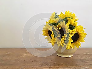 Yellow Sunflowers In Bloom In A Vintage Vase With A Neutral Background On A Warm Wooden surface