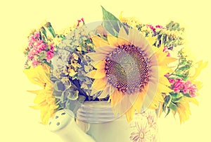 Yellow sunflowers and colored wild flowers in a white sprinkler, close up