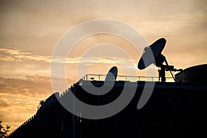 Yellow sunset with multiple satellite dishes antenna on the rooftop of