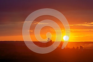 Yellow sunset over industrial landscape with factory chimneys and pipes with smoke polluting the atmosphere