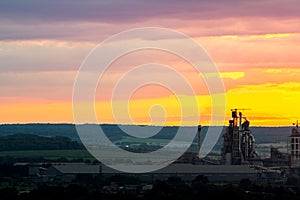 Yellow sunset over industrial landscape with factory chimneys and pipes with smoke polluting the atmosphere