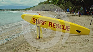 Yellow surfboard on beach with red text surf rescue emergency on a beach