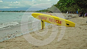 Yellow surfboard on beach with red text surf rescue emergency on a beach