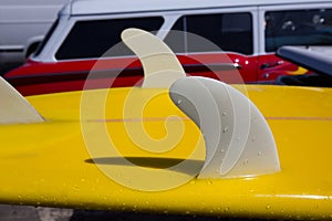 Yellow surfboard keel fins detail eith red retro car in Califor