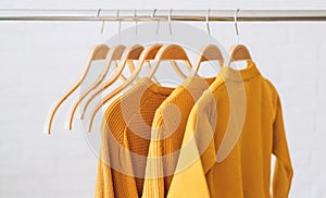 Yellow sweatshirts on wooden hangers hang on an iron bar rale photo