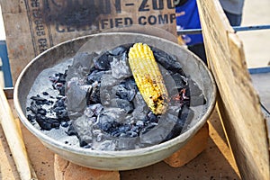 Yellow sweet corn roasted on fire from black carbons