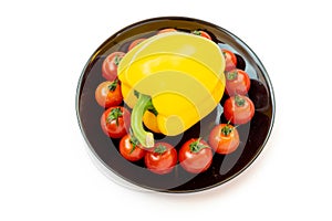 Yellow sweet pepper with tomatoes in a black plate isolated on white background. Composition of yellow peppers and red tomatoes on
