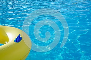 Yellow swim ring in a swimming pool with rippled water, background