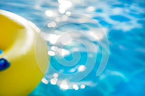 Yellow swim ring in a swimming pool with rippled water, background, blur focus