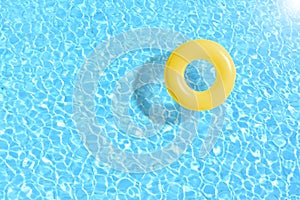 Yellow swimming pool ring float in blue water.