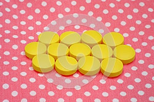 Yellow tablets pills on pink background
