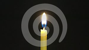 Yellow taper in the dark. A hand with a match lights a candle and it burns with an even flame.