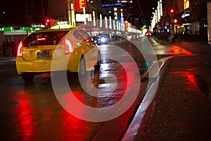 Yellow taxi car driving  rain night city wet asphalt red reflections copy space