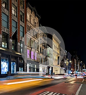 Yellow taxi with motion blur effect driving past the historic buildings on Broadway in the SoHo neighborhood of New York City at