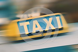 Yellow taxi sign on top of taxi cab. Fast public transport service car on city background