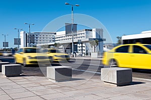 Yellow taxis driving on the street at the airport.