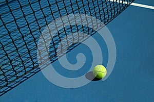 Yellow tennis ball is laying near black net. photo