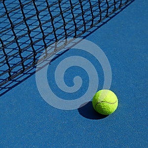 Yellow bright tennis ball is laying near black net. photo
