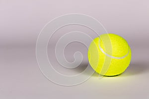 Yellow tennis ball on a light background. Close-up