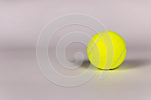 Yellow tennis ball on a light background. Close-up