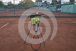 Yellow tennis balls in an iron basket and two tennis rackets