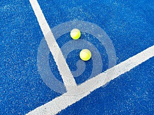 Yellow tennis balls, placed among white lines of a blue tennis court