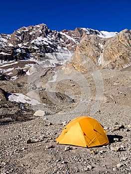 Yellow tent in the base camp under the peaks. Fan Mountains, Tajikistan