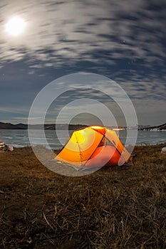 Yellow tent at night on the shore of lake Baikal in winter