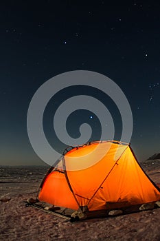 Yellow tent at night on the shore of lake Baikal in winter