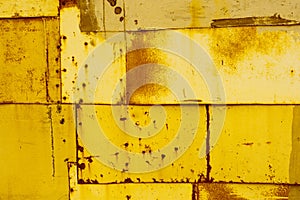 Yellow textural background of old rusty metal sheets fastened together with rivets and nails