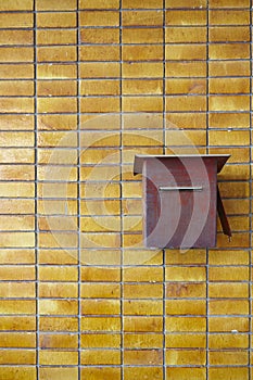 Yellow tiles wall with red rusty postbox