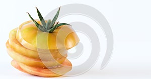 Yellow tomato cut in slices and stacked on white background. Health concept